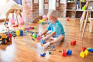 Young caucasian kid playing at kindergarten with toys. Preschooler boy happy at playroom