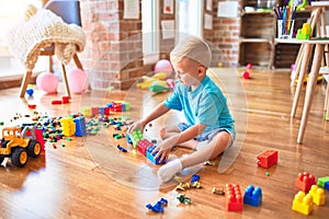 Young caucasian kid playing at kindergarten with toys. Preschooler boy happy at playroom