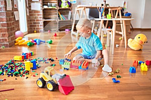 Young caucasian kid playing at kindergarten with toys. Preschooler boy happy at playroom