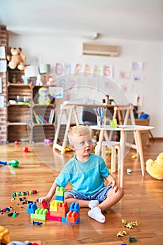 Young caucasian kid playing at kindergarten with toys. Preschooler boy happy at playroom