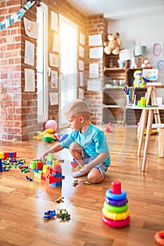 Young caucasian kid playing at kindergarten with toys. Preschooler boy happy at playroom