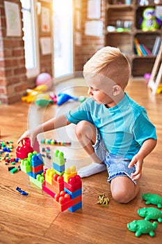 Young caucasian kid playing at kindergarten with toys. Preschooler boy happy at playroom