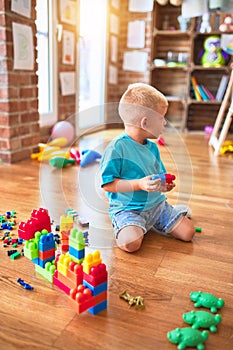 Young caucasian kid playing at kindergarten with toys. Preschooler boy happy at playroom