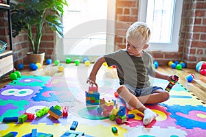 Young caucasian kid playing at kindergarten with toys. Preschooler boy happy at playroom