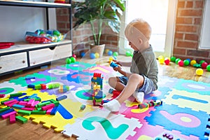 Young caucasian kid playing at kindergarten with toys. Preschooler boy happy at playroom