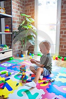 Young caucasian kid playing at kindergarten with toys. Preschooler boy happy at playroom