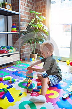 Young caucasian kid playing at kindergarten with toys. Preschooler boy happy at playroom