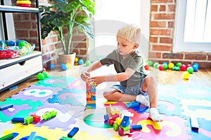 Young caucasian kid playing at kindergarten with toys. Preschooler boy happy at playroom