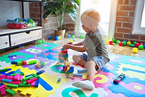 Young caucasian kid playing at kindergarten with toys. Preschooler boy happy at playroom