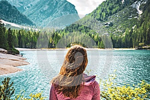 Young caucasian lady admiring the view of Baires Lake in the Dolomite mountains, South Tirol, Italy photo