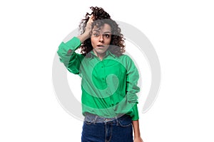 young caucasian lady with black curls dressed in a green blouse posing against a white background