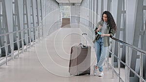 Young caucasian lady girl woman female passenger tourist traveler with suitcase stands in airport terminal holds