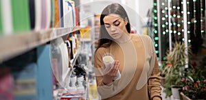 Young caucasian lady with a trolley and long hair in a supermarket chooses shampoo. A woman buys groceries and basic goods at a