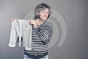 Young caucasian male boasting about new stylish baby clothes for his son holding in hands and demonstrating grey pants