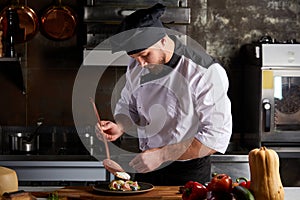 Young caucasian male chef adding piquancy to dish photo