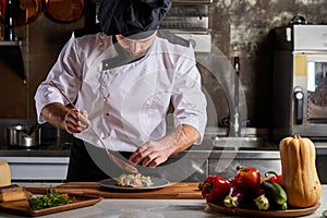 Young caucasian male chef adding piquancy to dish photo
