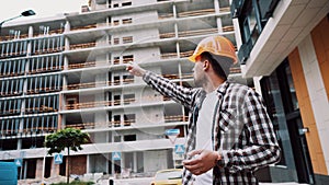 Young Caucasian male manager and supervisor at construction site leads process and gives instructions to subordinate workers.