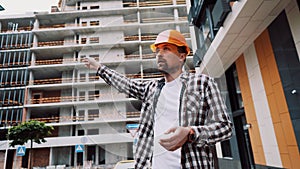 Young Caucasian male manager and supervisor at construction site leads process and gives instructions to subordinate workers.