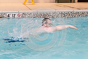 Young caucasian male in motion swimming in pool.