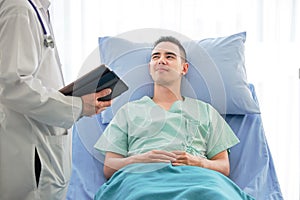 Young caucasian male patient on bed talking to doctor in hospital room