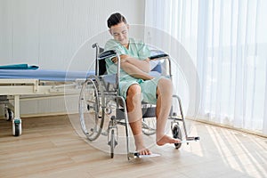 Young Caucasian male patient having arm pain,sitting on wheelchair in the hospita