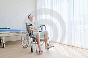 Young Caucasian male patient having stomachache ,sitting on wheelchair in the hospital room