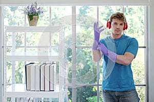 Young Caucasian male Wearing violet rubber gloves for clean of housework and relaxing for listening to music with red headphone.