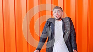 Young caucasian man afraid of fear, on an orange background, close-up, slow-mo, angst