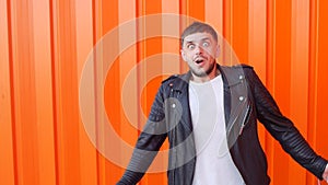 Young caucasian man afraid of fear, on an orange background, close-up, slow-mo, angst, lifestyle
