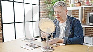 Young caucasian man applying make up sitting on table at dinning room