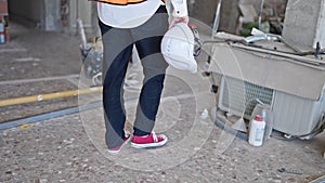 Young caucasian man architect holding hardhat walking at construction site