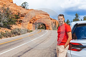 Young caucasian man in background of natural stone arch Bridge in the Red Canyon National Park in Utah, USA