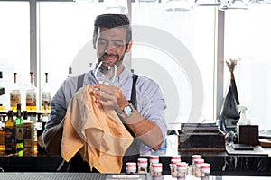 Young caucasian man is bartender cleaning and wipe glass with professional at counter.