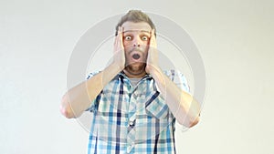 A young caucasian man with a beard experiences emotions of fear and surprise, close-up, white background, shock