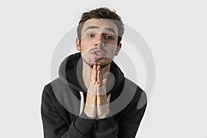 Young caucasian man is begging for something and looking into the camera. Isolated on white background. Begging concept