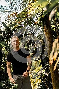 Young Caucasian man in a black shirt posing near the tree in Arhus City