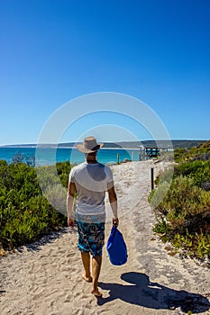 Young caucasian man with a blue bag walking down a pathway to Hamelin Beach. This Beach is famous for his stingrays, Hamelin Beach