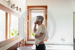Young Caucasian man brush teeth in modern bathroom