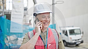 Young caucasian man builder smiling confident talking on smartphone at construction place