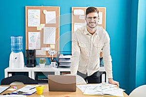 Young caucasian man business worker smiling confident standing by desk at office