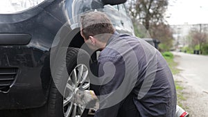 Young Caucasian Man changing tires on the car on the side of the road