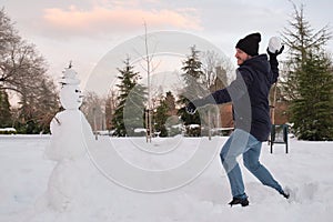 Young caucasian man destroying a smiley snowman with a hat during Filomena snowstorm in Madrid, Spain photo