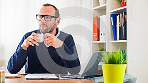 A young caucasian man drinking coffee in his office.