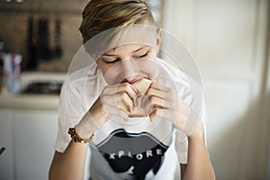 Young caucasian man eating sandwich in kitchen