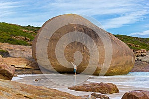 Young caucasian man in front of a huge rock at Lucky Bay, Cape Le Grand National Park near Esperance, Australia