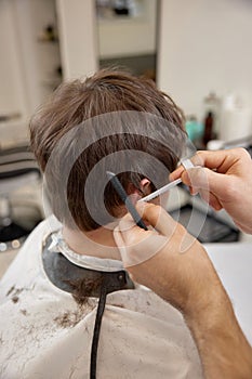 young caucasian man getting haircut by professional male hairstylist