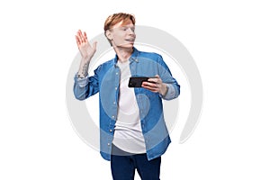 young caucasian man with golden red hair greets with hand holding phone