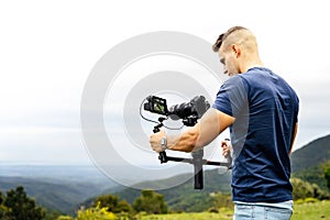 Young caucasian man handling a camera on top of a gimbal while working on recording a scene