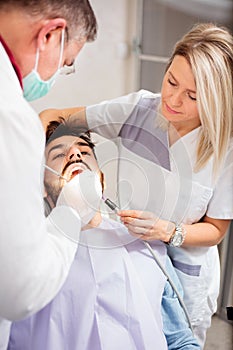 Young Caucasian man having his teeth examined in dental clinic