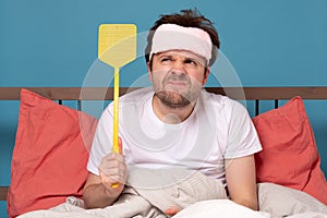 Man holding a fly swatter wanting to kill annoying mosquito photo